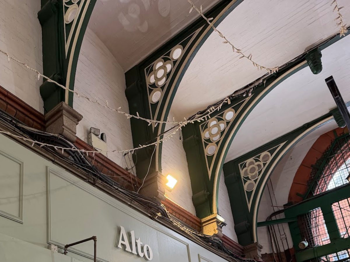 Dark green Victorian cast-iron arches and gothic quatrefoils above Alto's sign in George's Street Arcade.