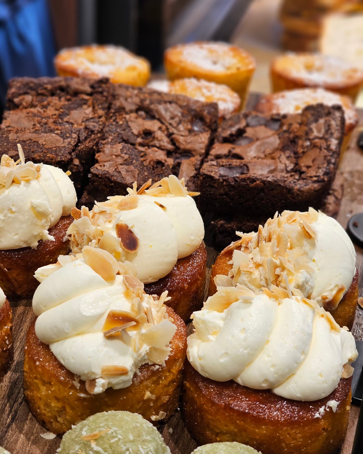 Brownies and almond traybakes with whipped cream in Alto's cake case.